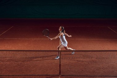 Spor sahasında tenis oynayan beyaz, profesyonel bir bayan.