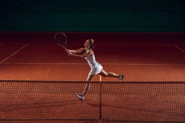 Young caucasian professional sportswoman playing tennis on sport court background