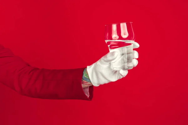 Female hand in white glove holding glass of pure water on red background — Stock Photo, Image