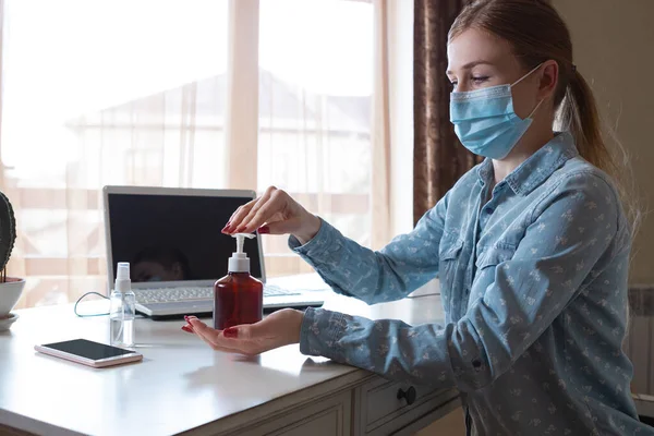 Young woman in face mask disinfecting gadgets surfaces on her workplace — Stock Photo, Image