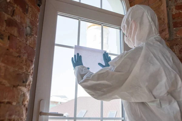 Coronavirus Pandemie. Een desinfector in een beschermend pak en masker maken van een waarschuwingsbord, copyspace — Stockfoto