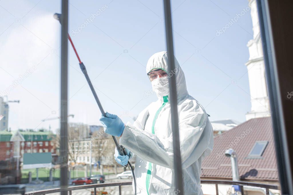 Coronavirus Pandemic. A disinfector in a protective suit and mask sprays disinfectants in the house or office
