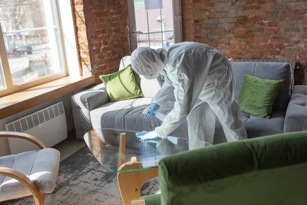 Coronavirus Pandemic. A disinfector in a protective suit and mask sprays disinfectants in the house or office — Stock Photo, Image