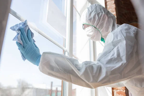 Pandemia por Coronavirus. Un desinfectante con traje protector y mascarilla pulveriza desinfectantes en la casa u oficina — Foto de Stock