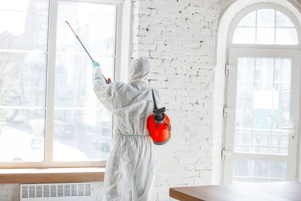 Coronavirus-Pandemie. Ein Desinfektor in Schutzanzug und Maske sprüht Desinfektionsmittel in Haus oder Büro — Stockfoto