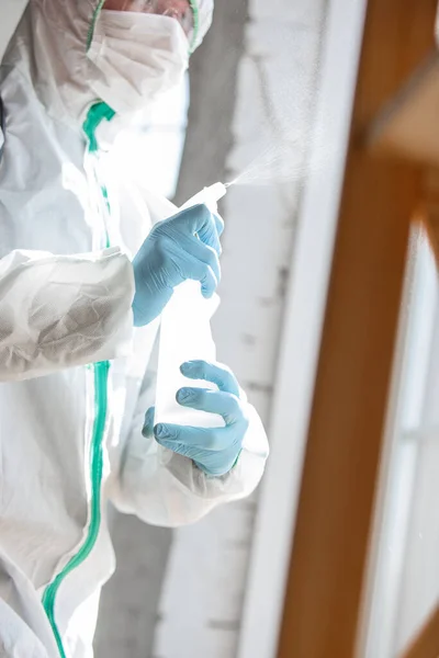 Coronavírus Pandémico. Um desinfetor em um terno protetor e máscara pulveriza desinfetantes na casa ou escritório — Fotografia de Stock