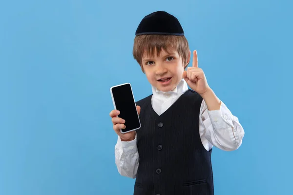 青いスタジオの背景に隔離された若い正統派ユダヤ人の少年の肖像、過越の祭りを満たす — ストック写真