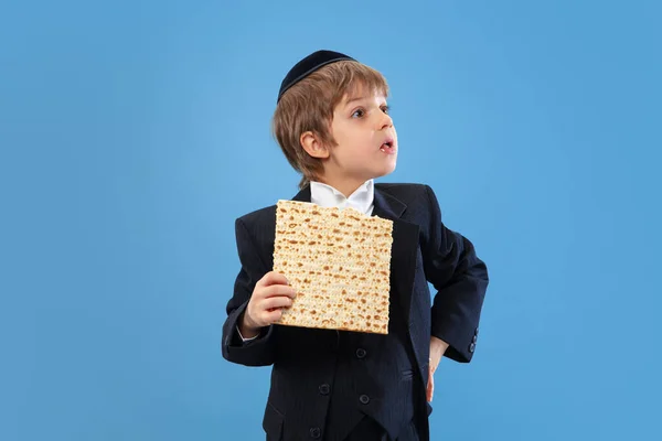 Portret van een jonge orthodoxe joodse jongen geïsoleerd op een blauwe studioachtergrond, die het Pascha ontmoet — Stockfoto