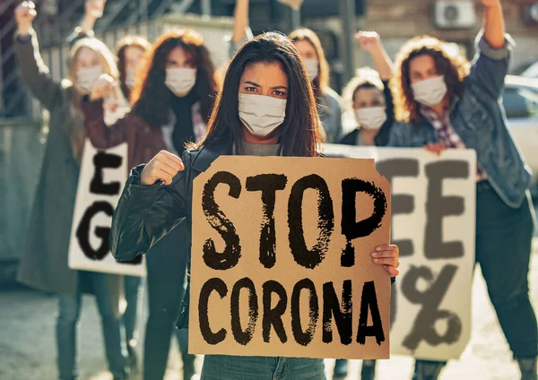 Unga människor i ansiktsmasker protesterar mot stoppet för coronavirus pandemi på gatan — Stockfoto