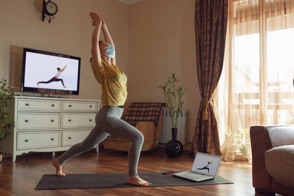 Sportos fiatal nő vesz jóga órák online és gyakorlat otthon, miközben a karantén — Stock Fotó
