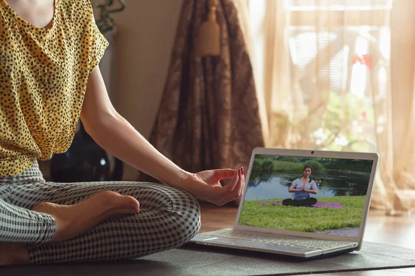 Sportig ung kvinna som tar yogalektioner online och övar hemma medan hon är karantän — Stockfoto