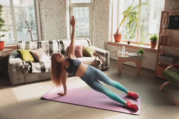 Mujer joven que enseña en casa cursos en línea de fitness, aeróbico, estilo de vida deportivo mientras está en cuarentena — Foto de Stock