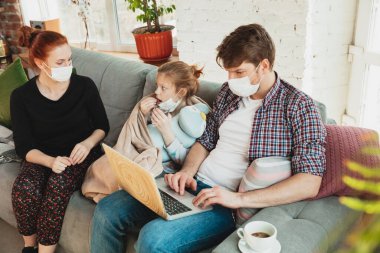 Korunaklı maskeli ve eldivenli beyaz aile evde koronavirüs semptomları ve tedavisi ile izole edilmiş.