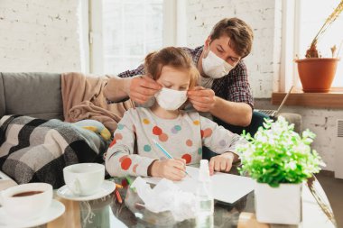 Koruyucu maskeli ve eldivenli baba ve kızı evde koronavirüs belirtileriyle izole edilmiş, salgını durdurun.