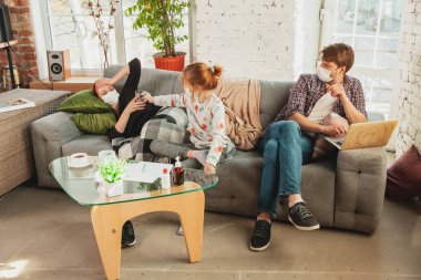 Korunaklı maskeli ve eldivenli beyaz aile evde koronavirüs semptomları ve tedavisi ile izole edilmiş.