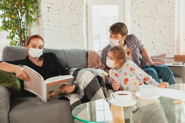 Korunaklı maskeli ve eldivenli beyaz aile evde koronavirüs semptomları ve tedavisi ile izole edilmiş.