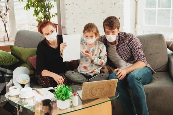 Caucasian family in protective masks and gloves isolated at home with coronavirus symptoms, treatment