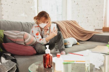 Korunaklı maskeli küçük bir kız koronavirüs semptomlarıyla evde izole edilmiş, salgını durdurun.