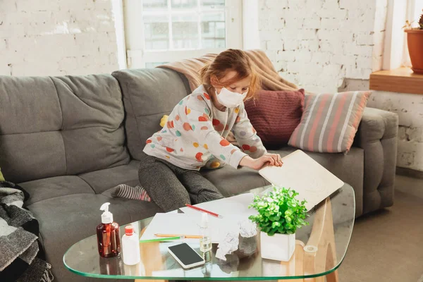 Dziewczynka w masce ochronnej izolowana w domu z objawami koronawirusowymi, powstrzymuje epidemię — Zdjęcie stockowe