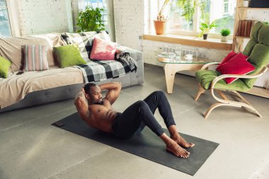 Genç Afro-Amerikalı erkek karantinadayken evde online spor, aerobik ve sportif yaşam dersleri veriyor.