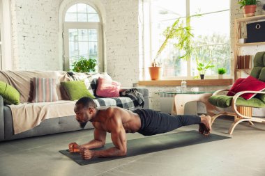 Genç Afro-Amerikalı erkek karantinadayken evde online spor, aerobik ve sportif yaşam dersleri veriyor.