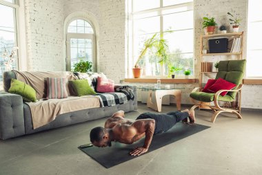 Genç Afro-Amerikalı erkek karantinadayken evde online spor, aerobik ve sportif yaşam dersleri veriyor.