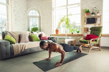 Genç Afro-Amerikalı erkek karantinadayken evde online spor, aerobik ve sportif yaşam dersleri veriyor.