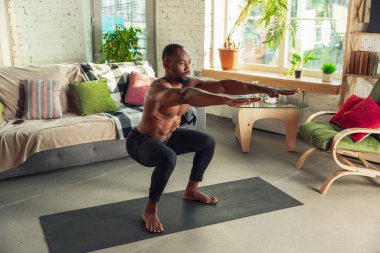Genç Afro-Amerikalı erkek karantinadayken evde online spor, aerobik ve sportif yaşam dersleri veriyor.