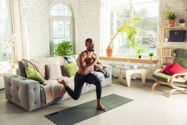 Genç Afro-Amerikalı erkek karantinadayken evde online spor, aerobik ve sportif yaşam dersleri veriyor.
