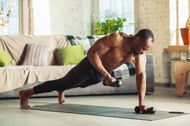 Genç Afro-Amerikalı erkek karantinadayken evde online spor, aerobik ve sportif yaşam dersleri veriyor.