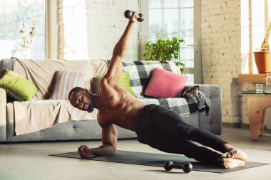 Genç Afro-Amerikalı erkek karantinadayken evde online spor, aerobik ve sportif yaşam dersleri veriyor.