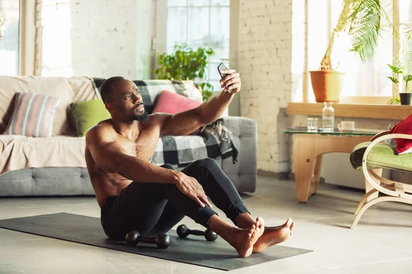 Jonge Afrikaans-Amerikaanse man onderwijs thuis online cursussen van fitness, aërobe, sportieve levensstijl, terwijl het zijn quarantaine — Stockfoto