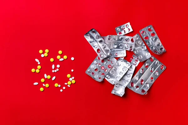 Píldoras, tabletas y cápsulas de color sobre un fondo rojo: historial de tratamiento, prevención de pandemias — Foto de Stock