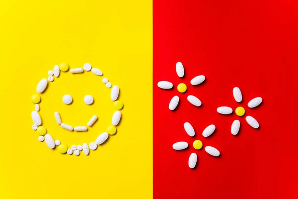 Colored pills, tablets and capsules on a red and yellow background - history of treatment, prevention of pandemic