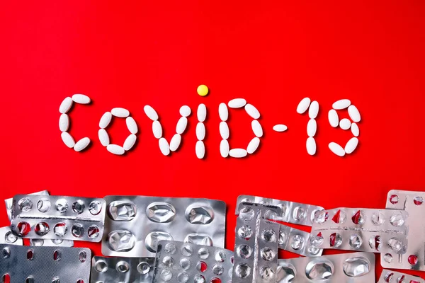 Colored pills, tablets and capsules on a red background - history of treatment, prevention of pandemic