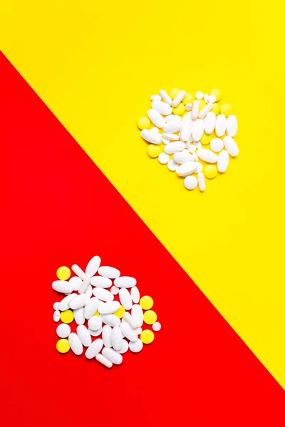 Pastillas, tabletas y cápsulas de color sobre un fondo rojo y amarillo: historial de tratamiento, prevención de pandemias — Foto de Stock