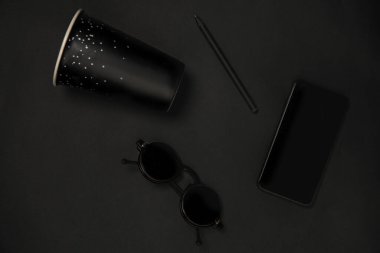 Gadget, kahve ve gözlük. Siyah renkte tek renkli kompozisyonda. Üst manzara, düz uzanma.