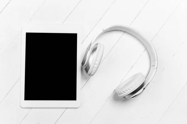 Tableta y auriculares. Composición elegante monocromática en color blanco. Vista superior, plano . —  Fotos de Stock