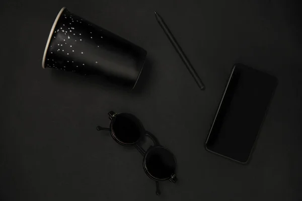 Gadget, koffie en brillen. Monochrome stijlvolle compositie in zwarte kleur. Bovenaanzicht, vlak lay. — Stockfoto