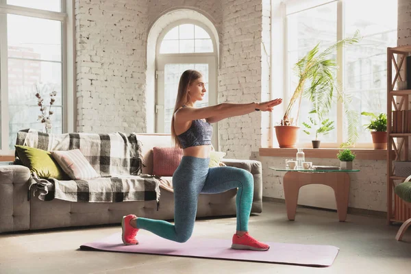 Mujer joven que enseña en casa cursos en línea de fitness, aeróbico, estilo de vida deportivo mientras está en cuarentena — Foto de Stock