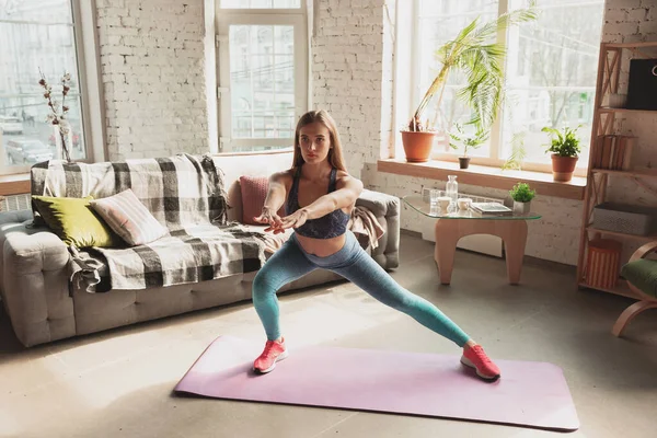 Mujer joven que enseña en casa cursos en línea de fitness, aeróbico, estilo de vida deportivo mientras está en cuarentena — Foto de Stock