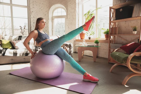 Mujer joven que enseña en casa cursos en línea de fitness, aeróbico, estilo de vida deportivo mientras está en cuarentena — Foto de Stock