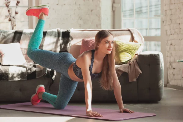 Mujer joven que enseña en casa cursos en línea de fitness, aeróbico, estilo de vida deportivo mientras está en cuarentena — Foto de Stock