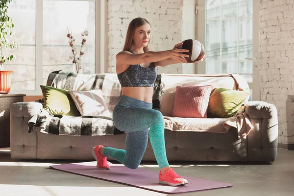 Mujer joven que enseña en casa cursos en línea de fitness, aeróbico, estilo de vida deportivo mientras está en cuarentena — Foto de Stock