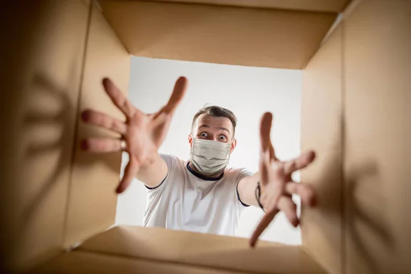 Ung man öppnar enorma postpaket bär skyddande ansiktsmask, kontaktlös leverans — Stockfoto