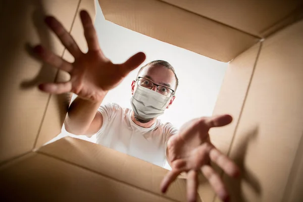 Ung man öppnar enorma postpaket bär skyddande ansiktsmask, kontaktlös leverans — Stockfoto