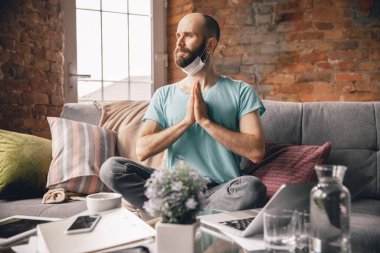 Evde yoga yapan genç bir adam karantina altında ve serbest çalışıyor.