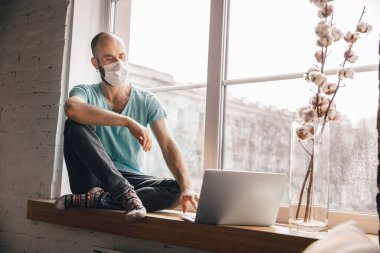 Evde yoga yapan genç bir adam karantina altında ve serbest çalışıyor.