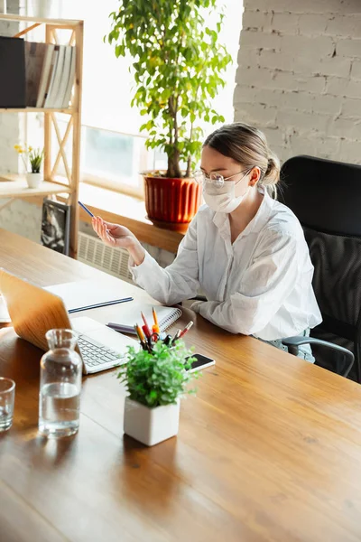 Woman working in office alone during coronavirus or COVID-19 quarantine, wearing face mask — Stock Photo, Image