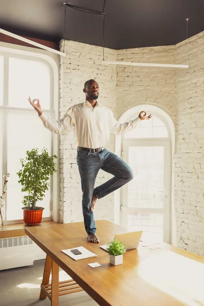 Junger afrikanisch-amerikanischer Mann macht Yoga zu Hause, während er unter Quarantäne steht und freiberuflich arbeitet — Stockfoto